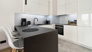 A modern kitchen with white cabinetry, a dark countertop, and a central island with seating.