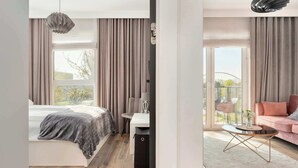 A modern bedroom with a bed, bedside table, and a view of a balcony.