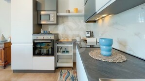 Una cocina moderna con horno empotrado, microondas y cafetera sobre una encimera.