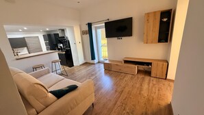 Uma sala de estar moderna com um sofá, uma TV fixada na parede e um móvel de entretenimento em madeira.