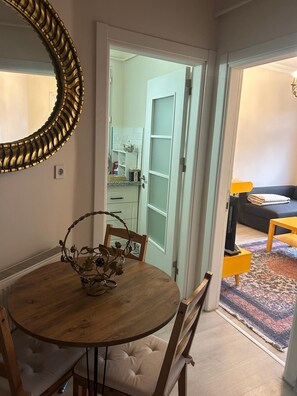 A dining area with a round wooden table, chairs, and a decorative centerpiece. A large mirror with a gold frame is on the wall. - Bohemian Antique House in Colorful Balat (İstanbul)