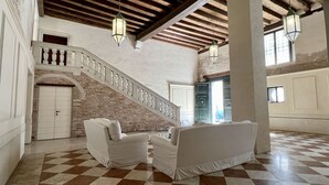 A spacious lobby with a checkered floor, a staircase with a white balustrade, and hanging lanterns.