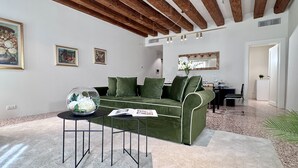 A living room with a green sofa, a glass bowl with flowers, and a magazine on a side table.