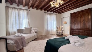 A hotel room with two beds, a chair, a floor lamp, and a wooden wardrobe.