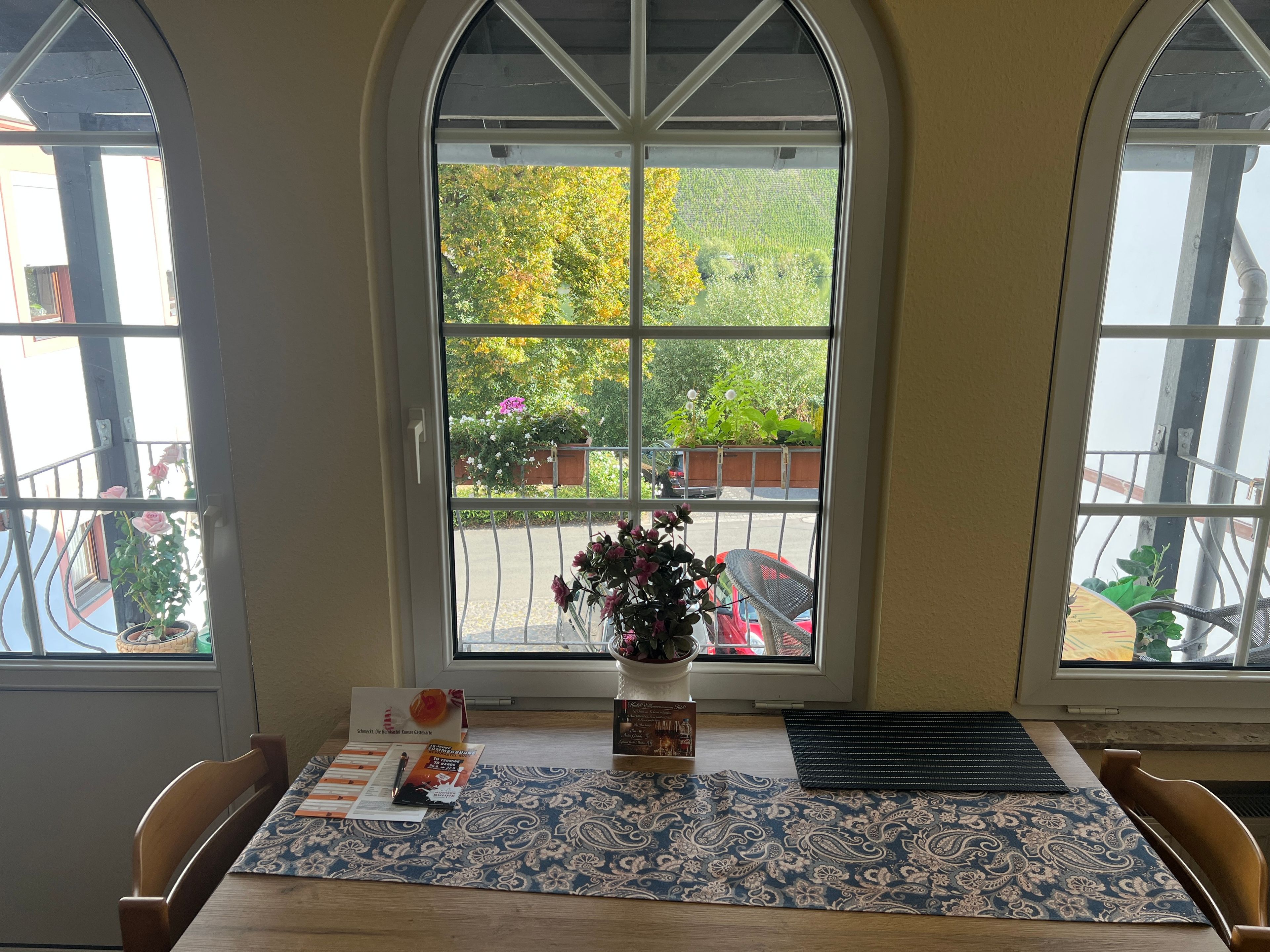 Une table avec un chemin de table à motifs, un vase de fleurs et un menu posé sur la table.