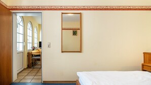 A hotel room with a bed, a mirror, and a door leading to a dining area. - Apartment "Ferienwohnung 2" with Balcony, Moselle & Mountain Views, Shared Terrace, and Wi-Fi (Bernkastel-Kues)