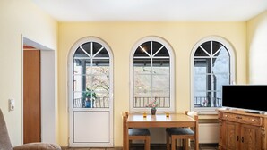 A room with a dining table, two chairs, a TV, and a cabinet. - Apartment "Ferienwohnung 2" with Balcony, Moselle & Mountain Views, Shared Terrace, and Wi-Fi (Bernkastel-Kues)