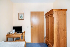 A room with a bed, a desk with a laptop, a wooden wardrobe, and a door. - Room 'Einzelzimmer 4' with Mountain View, Shared Terrace and Wi-Fi (Bernkastel-Kues)