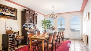 A dining room with a large table, chairs, a chandelier, a fireplace, and a view through arched windows. - Room 'Einzelzimmer 4' with Mountain View, Shared Terrace and Wi-Fi (Bernkastel-Kues)