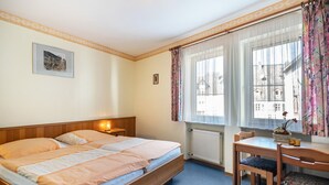A bedroom with a bed, bedside table, chair, window with curtains, and a radiator. - Room “Gastzimmer 3” with Shared Terrace and Wi-Fi (Bernkastel-Kues)