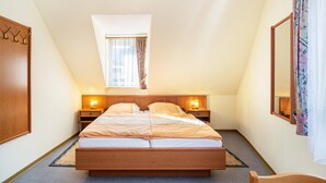 Een slaapkamer met een bed, nachtkastjes, een raam, een spiegel en een stoel.