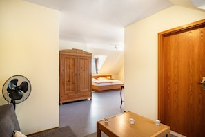 Un dormitorio con un armario de madera, una mesita de noche con vasos, un ventilador y una cama con cabecero.