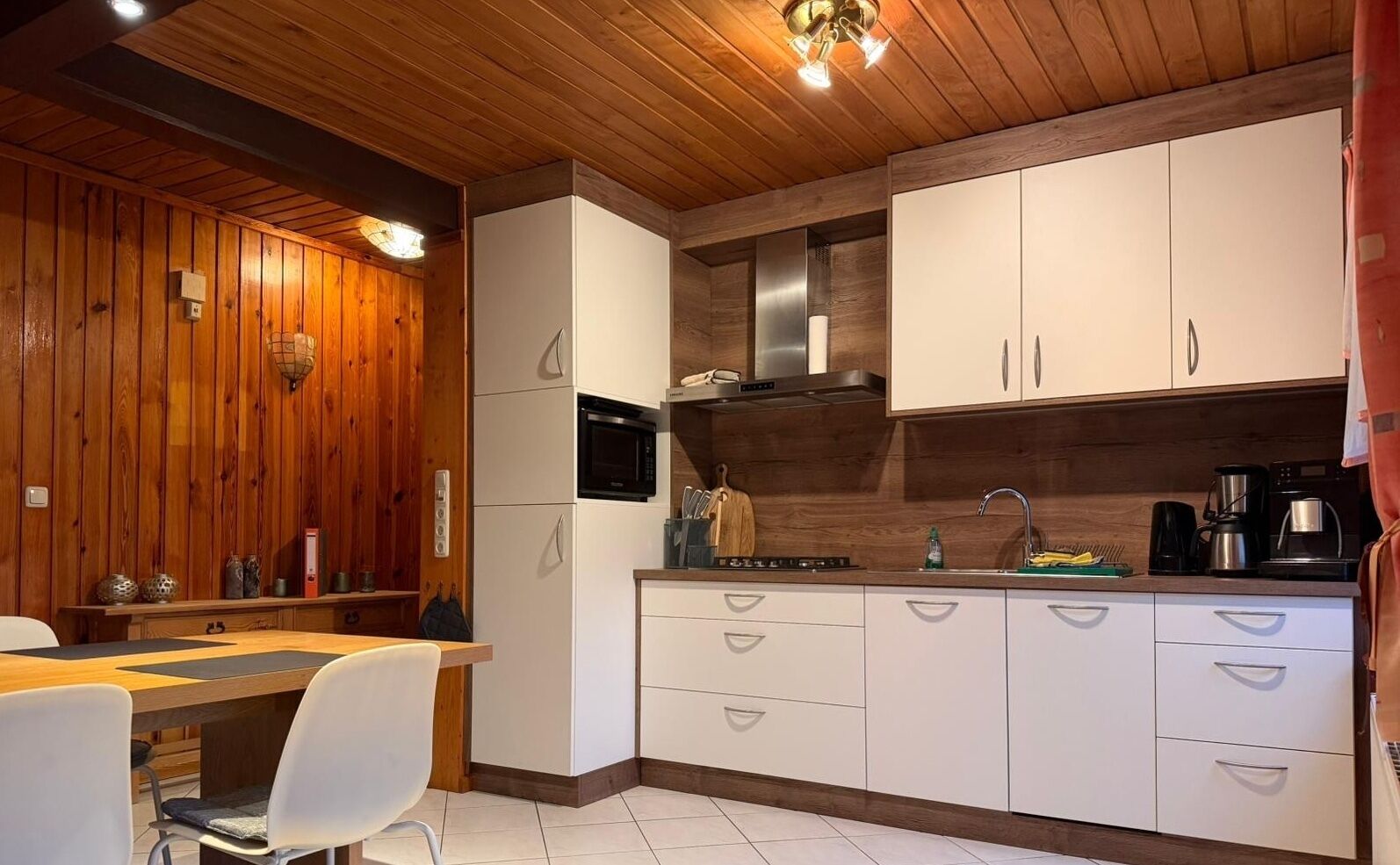 Eine moderne Küche mit Holzvertäfelung, weißen Schränken, einer Mikrowelle und einem Spülbecken.