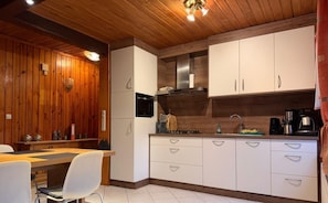 Una cocina moderna con paneles de madera, armarios blancos, un microondas y un lavamanos.