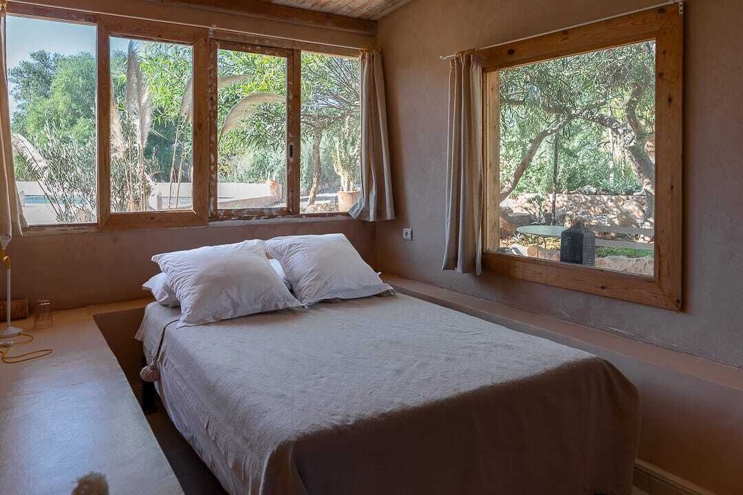A bedroom with a bed, a window, and a view of trees.