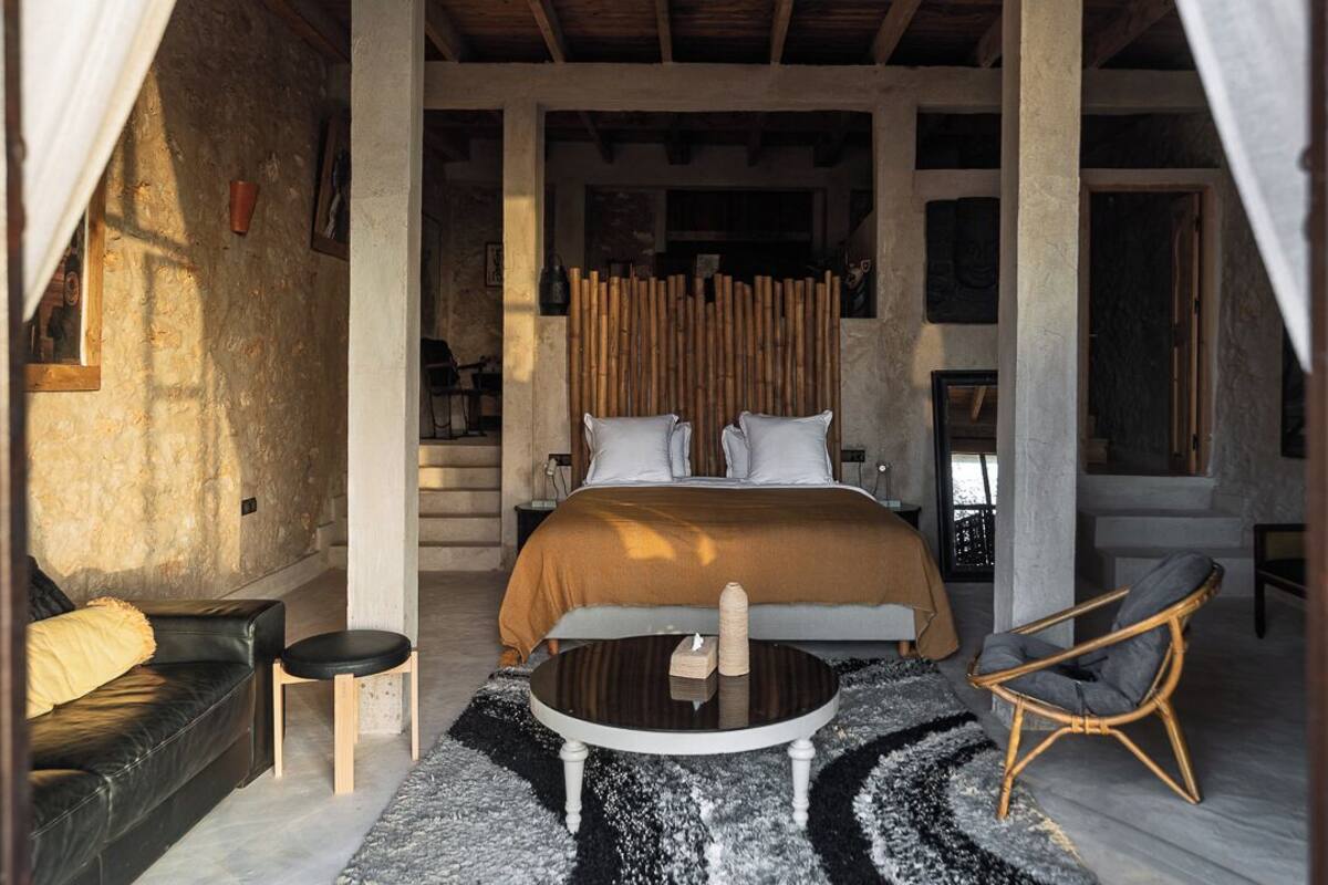 A bedroom with a bed, a round table, a sofa, and a chair.