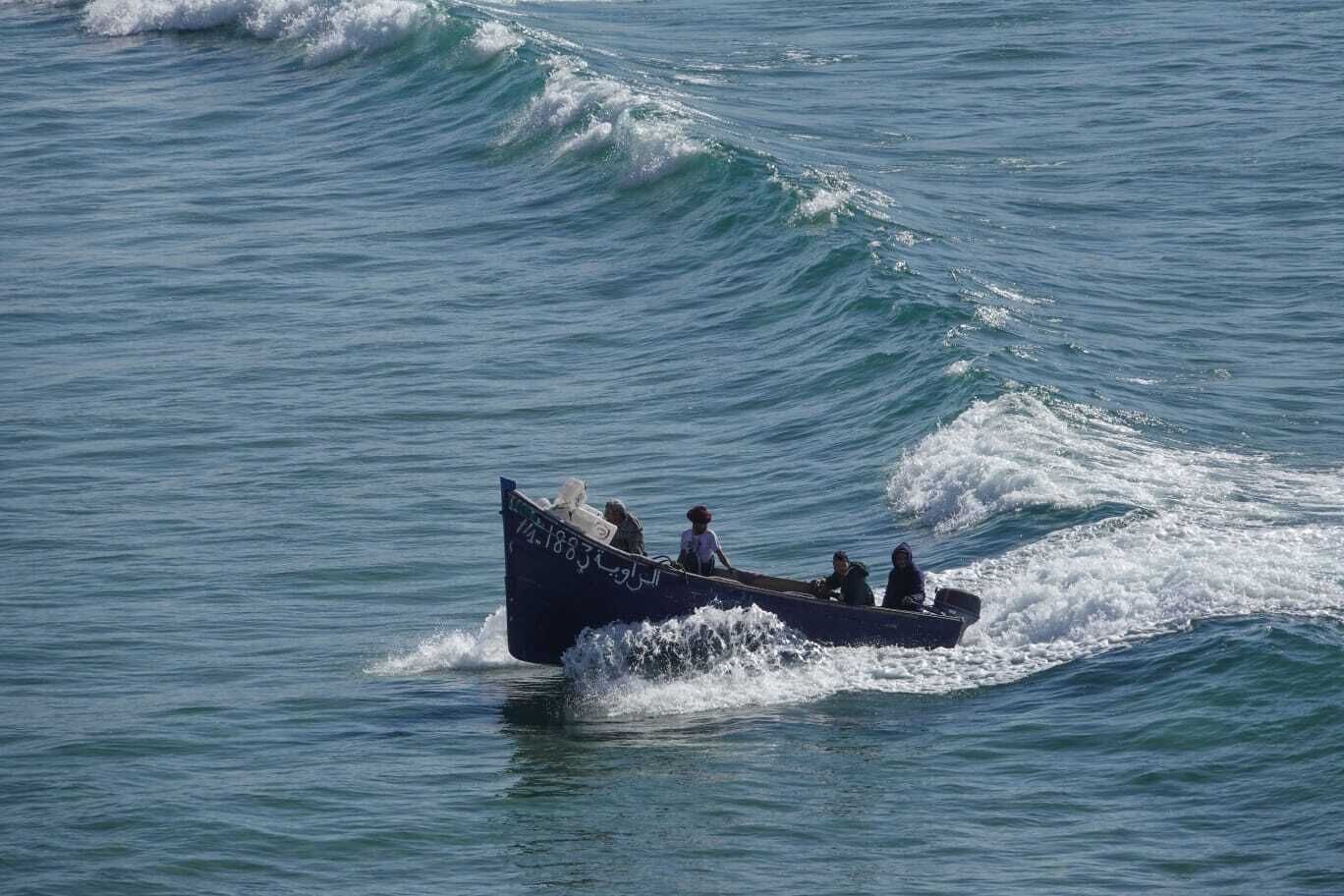 A small boat with several people on it, moving through the water.