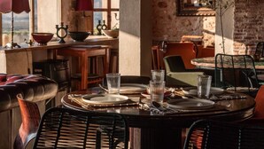 Un comedor rústico con una mesa de madera dispuesta para cuatro personas, rodeado de sillas de mimbre.