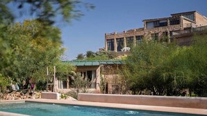 Zona de piscina con un edificio de piedra al fondo.
