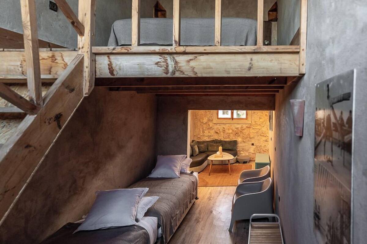 A compact room with bunk beds, a small seating area, and a ladder.