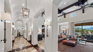 A spacious hallway with a tiled floor, a dining area with a large window, and a living room with a sofa and a coffee table. - Luxury 6BR Mesa Estate | Pool, Water Slide, Pickleball, Theater (Mesa)