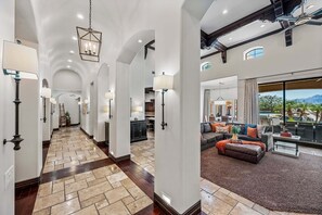 A spacious hallway with a tiled floor, a dining area with a large window, and a living room with a sofa and a coffee table.