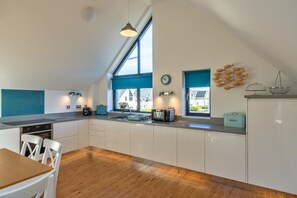 Eine moderne Küche mit weißen Schränken, einem Holzespeisetisch und einem großen Fenster, das für natürliches Licht sorgt.