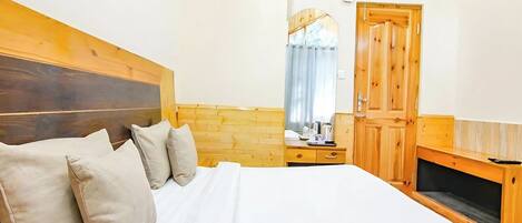 A bedroom with a wooden headboard, a bed with white linens, a wooden dresser, and a wooden door.