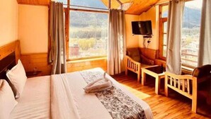 Una habitación de madera con una cama, un televisor y vistas a la montaña.