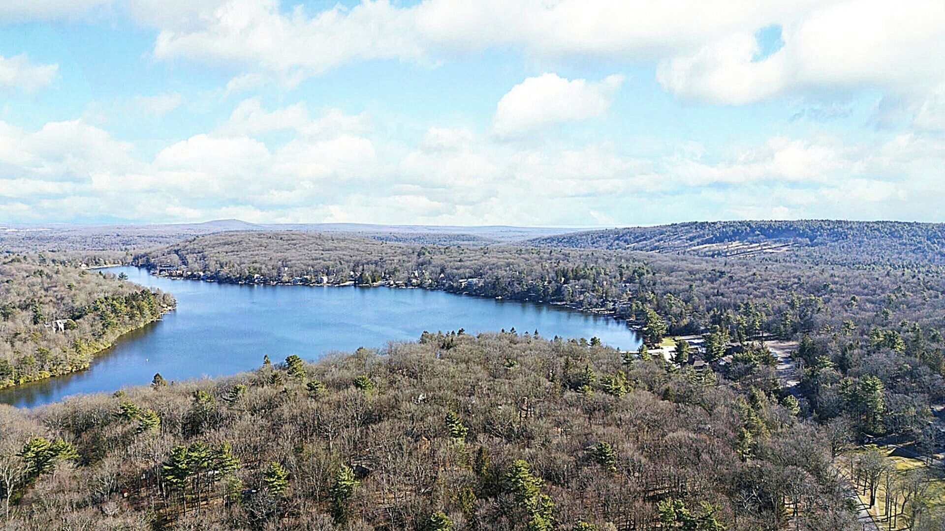 A lake surrounded by forested hills with a clear sky.