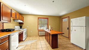 Una cocina pequeña con armarios de madera, estufa, refrigerador y ventana con persianas.