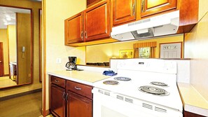 A compact kitchen with wooden cabinets, a white stove, and a coffee maker. - Spacious Two‑Story Townhouse Close to Skiing, Waterparks & Hiking (Lake Harmony)