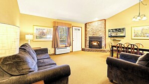A cozy living room with a fireplace, comfortable seating, and artwork on the walls. - Spacious Two‑Story Townhouse Close to Skiing, Waterparks & Hiking (Lake Harmony)