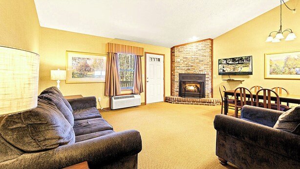 A living room with a fireplace, a dining table, and two sofas. - Bi‑Level Retreat w/ Private Sauna Near Top Poconos Attractions (Lake Harmony)