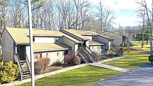 A row of single-story, two-bedroom apartment buildings with front porches and a small front yard. - Bi‑Level Retreat w/ Private Sauna Near Top Poconos Attractions (Lake Harmony)
