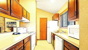 A compact kitchen with wooden cabinets, a refrigerator, a microwave, and a stove. - Bi‑Level Retreat w/ Private Sauna Near Top Poconos Attractions (Lake Harmony)