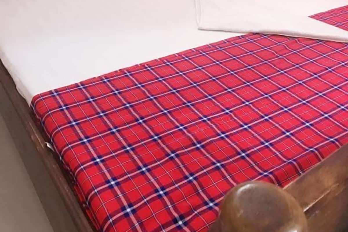 A bed with a red plaid bedspread, white pillows, and a wooden headboard.