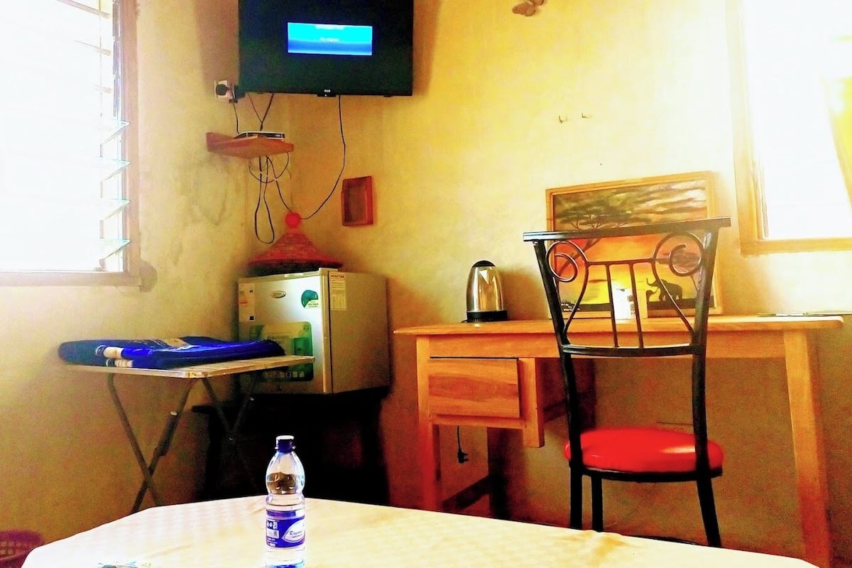 A small room with a desk, chair, and a television mounted on the wall.