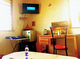 Una habitación pequeña con un escritorio, una silla y un televisor montado en la pared.