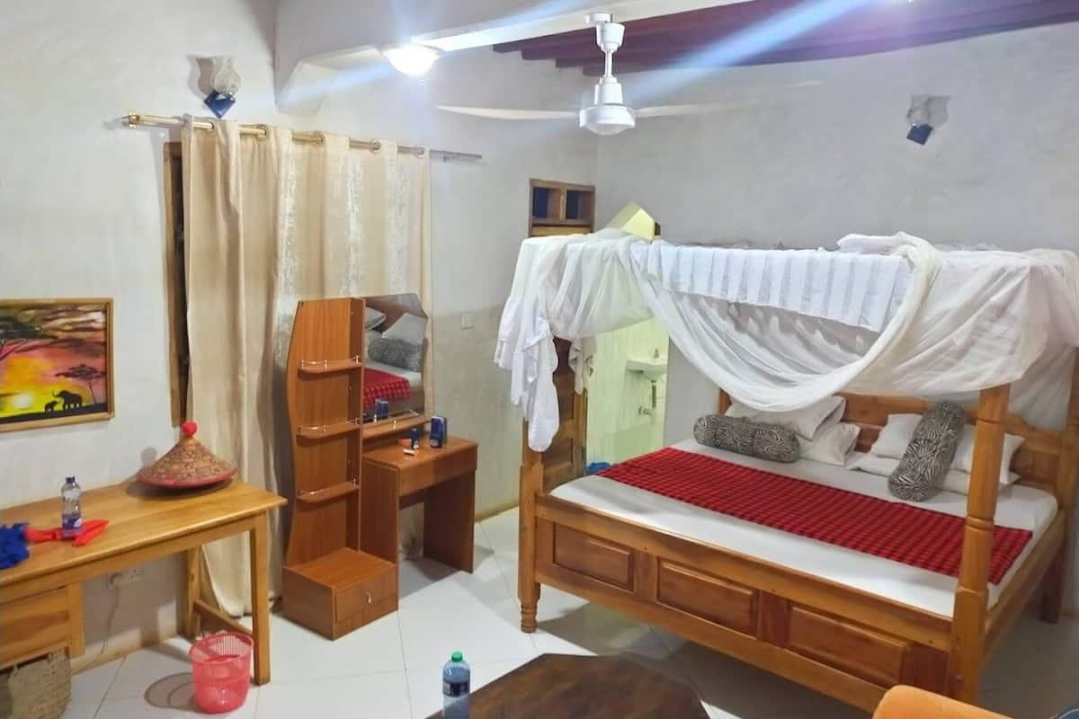 A bedroom with a bed, a desk, a chair, and a ceiling fan.