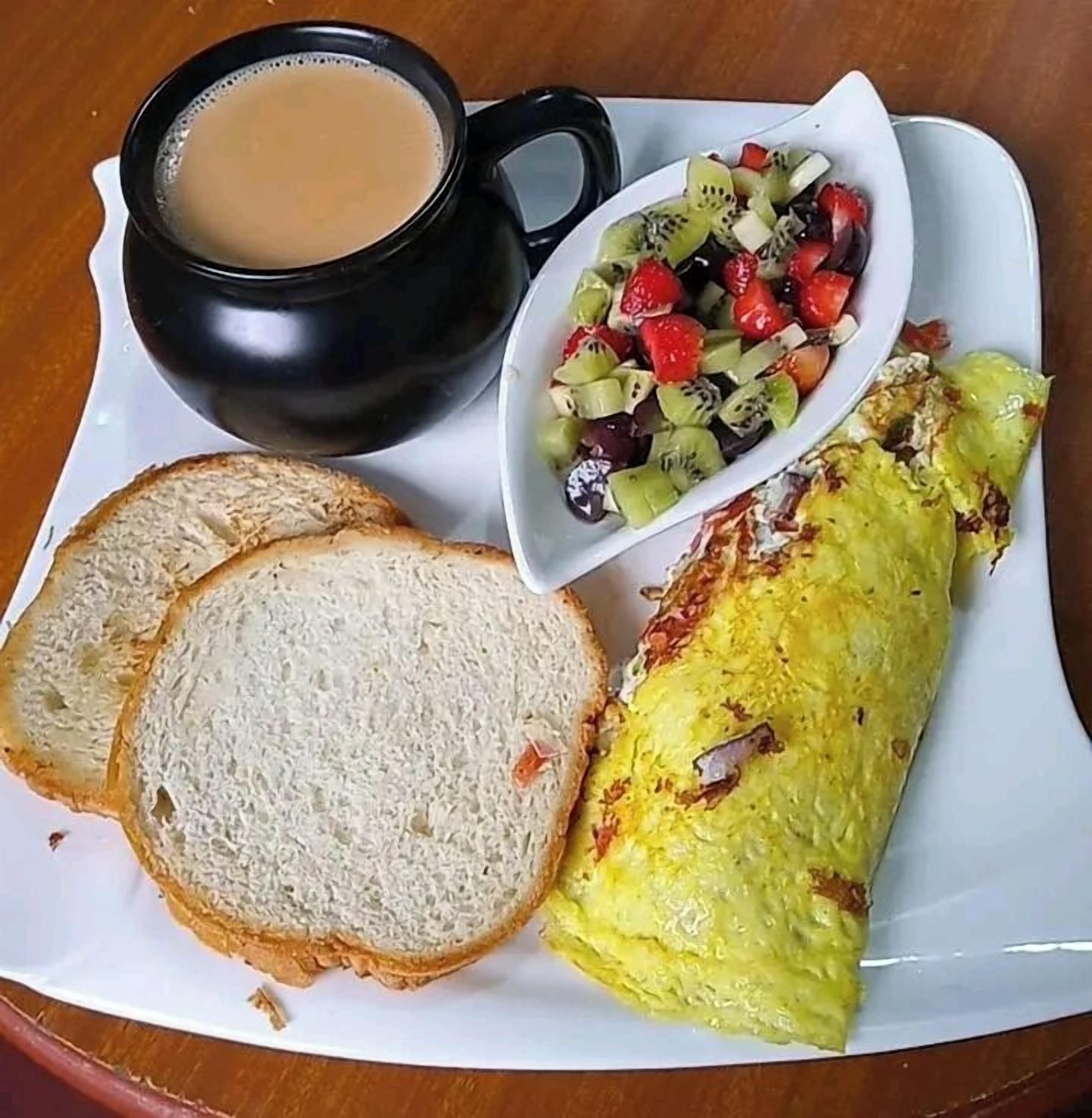 Une assiette avec une omelette, des toasts et une salade de fruits.