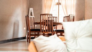 Een eethoek met een tafel, stoelen, een lamp en een raam met gordijnen.