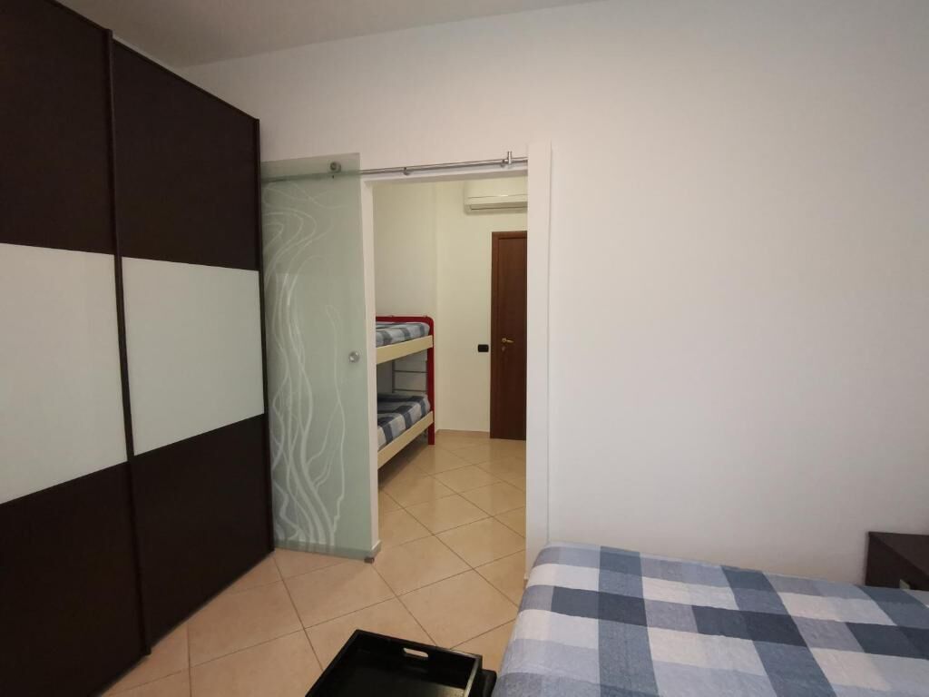 Een slaapkamer met een bed, een kledingkast en een stapelbed op de achtergrond.