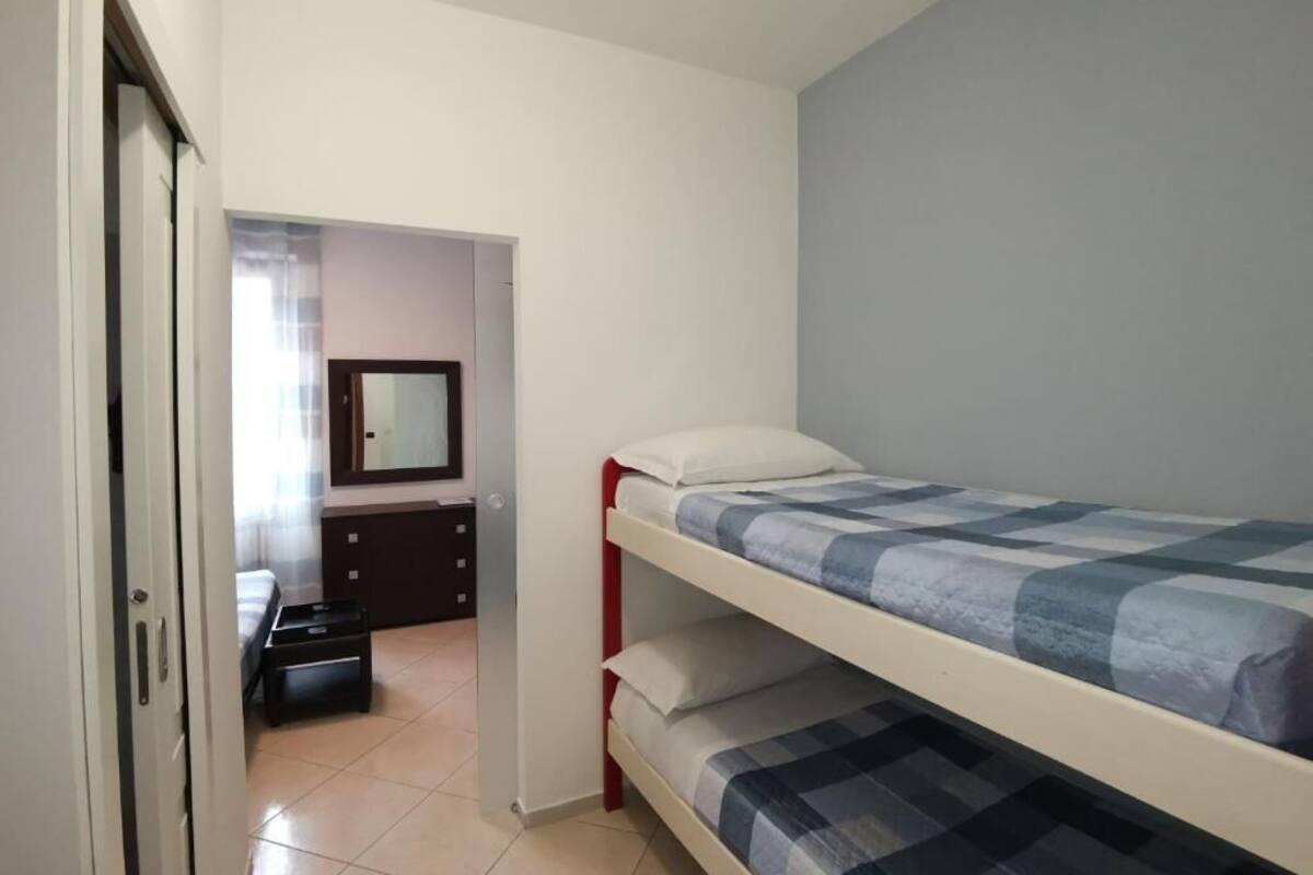 Ein Schlafsaalzimmer mit einem Etagenbett, einem Schminktisch, einem Spiegel und einer Tür zu einem anderen Raum.