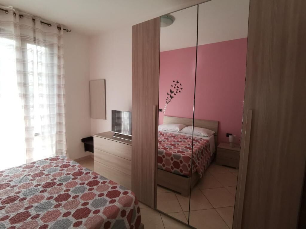 A bedroom with a bed, a dresser, a mirror, and a wardrobe.
