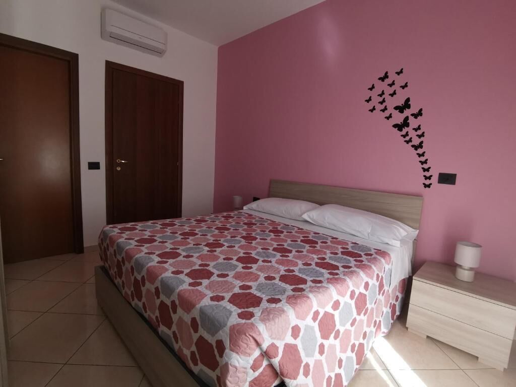 Une chambre à coucher avec un lit, une table de chevet et un mur décoré d’autocollants représentant des papillons.