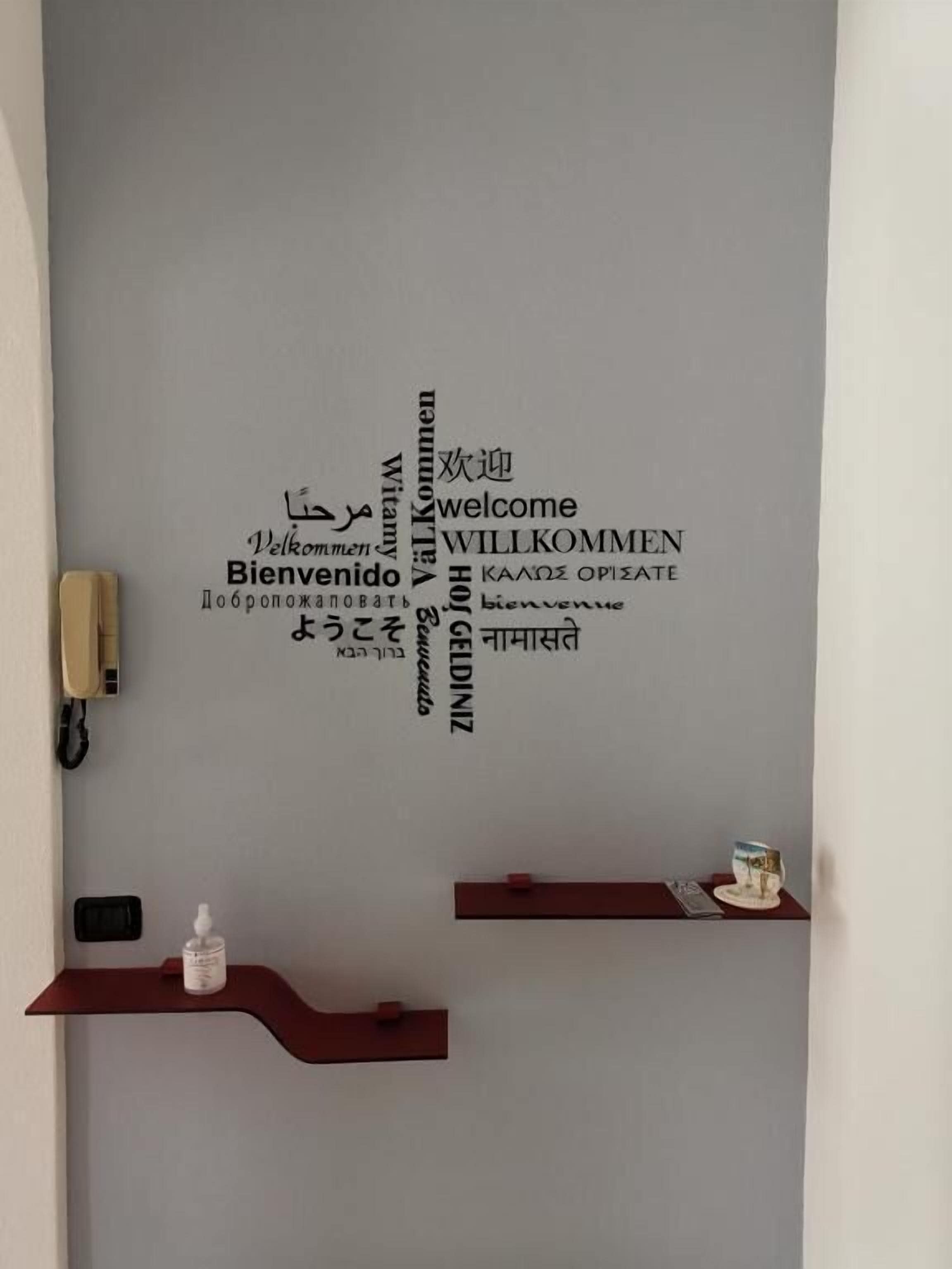 A wall with multilingual welcome signs and a phone on a desk.