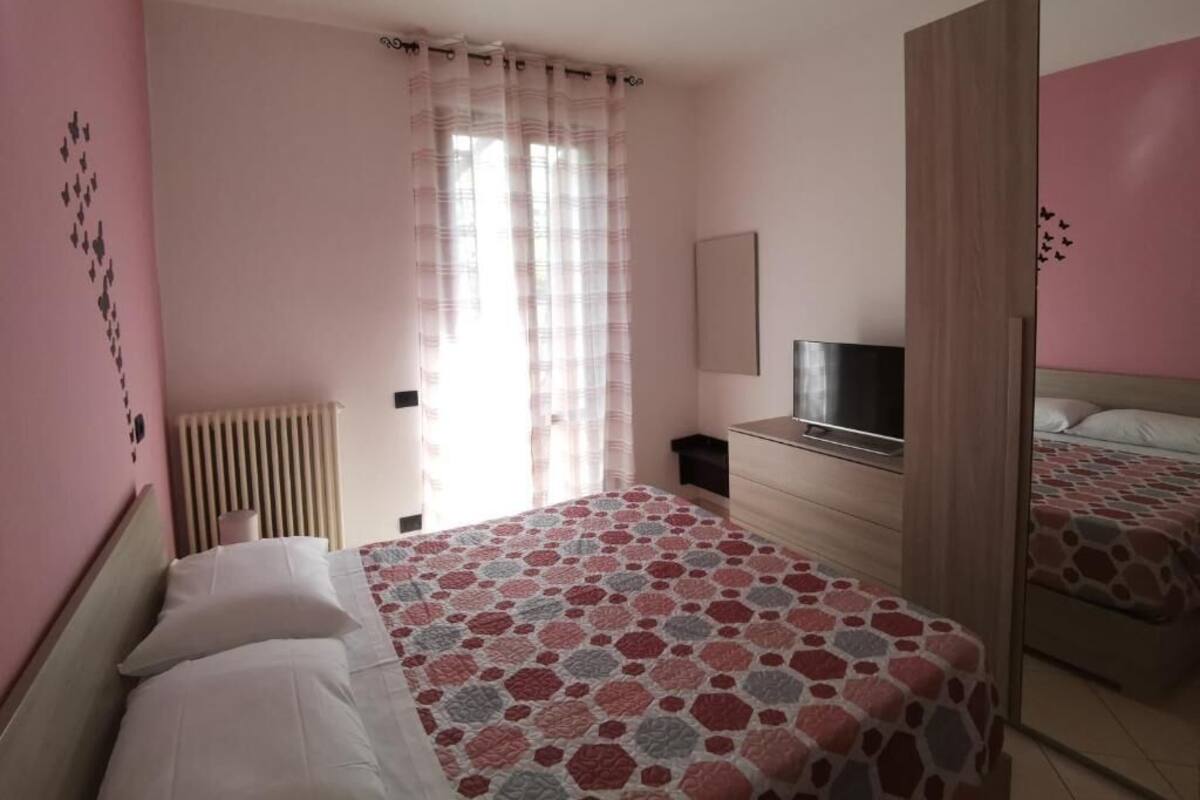 Ein Schlafzimmer mit einem Bett, einem Schminktisch, einem Fernseher und einem Spiegel.