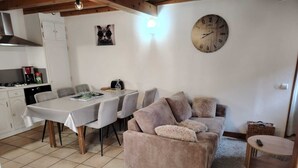 Ein gemütlicher Wohnbereich mit Esstisch, Stühlen, einer Couch und einer Uhr an der Wand.