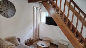 Ein Wohnzimmer mit einer Holztreppe, einem runden Couchtisch, einem Sofa und einer Wanduhr.